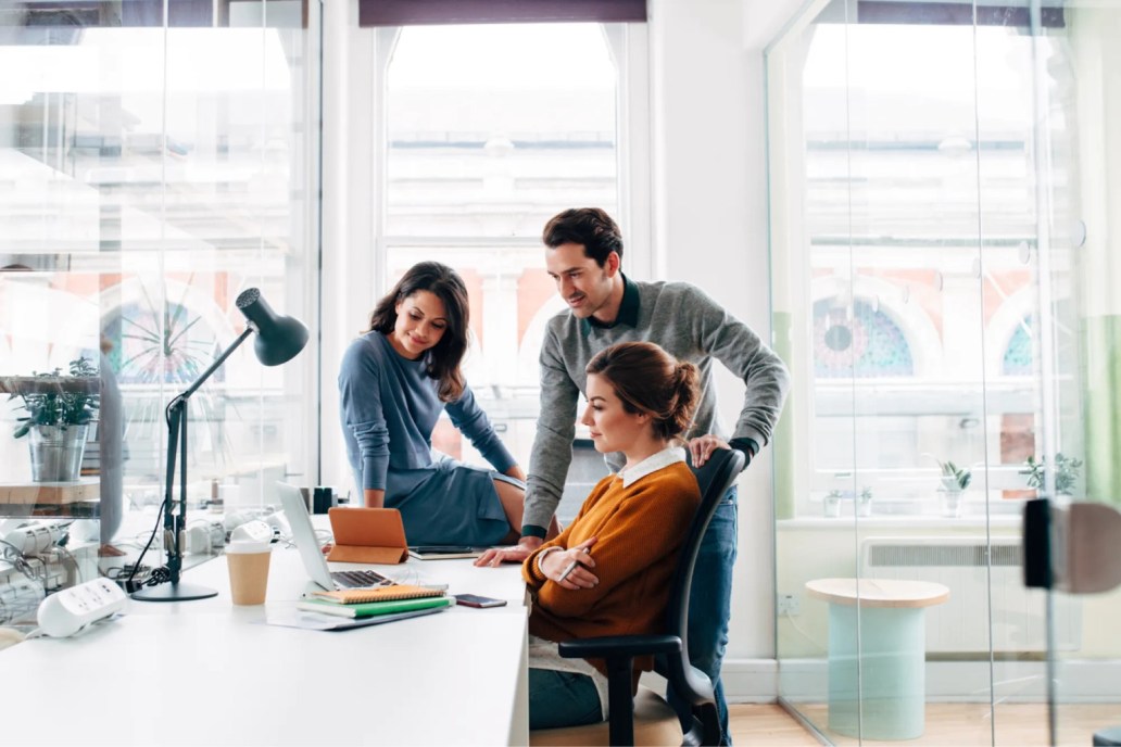 Three people in an office looking at a computer.